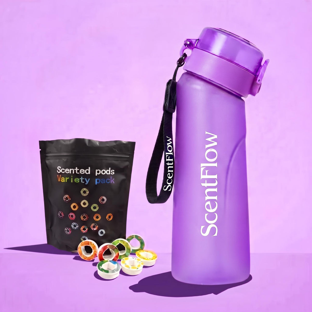 A purple ScentFlow insulated water bottle with a matching purple lid and wrist strap, shown next to a black ScentFlow pouch labeled 'Scented pods Variety pack' with several colorful pods scattered in front, on a lavender background.